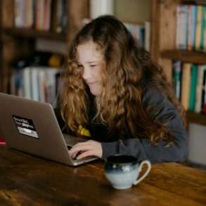 Teenage girl sitting in a library at a laptop