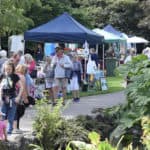 People walking through the park on Ventnor Day, with stall in the background