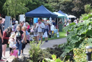 People walking through the park on Ventnor Day, with stall in the background