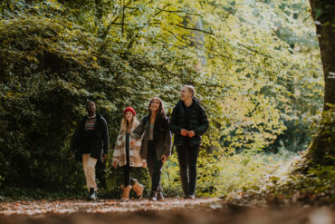 Four young people walking through woodland
