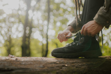 Person resting their foot on a tree trunk whilst they do up the laces of their walking boots