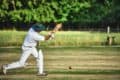 cricket match taking place on green