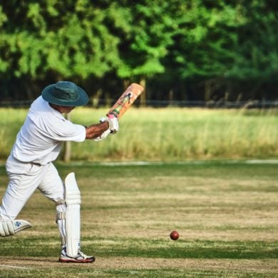 cricket match taking place on green