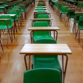 desks lined up in sports hall for examinations