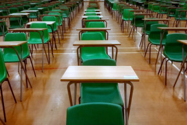 desks lined up in sports hall for examinations