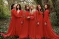 The Mediaeval Baebes standing in the woods, all dressed in long red dresses