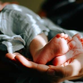 Adult hand holding baby's feet