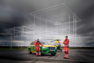 Ambulance staff in front of a car and helicopter and sketch outline on top of airbase