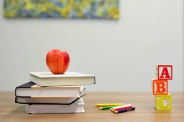 Books and apple and ABC blocks on a school desk