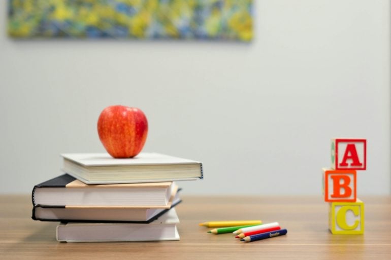 Books and apple and ABC blocks on a school desk