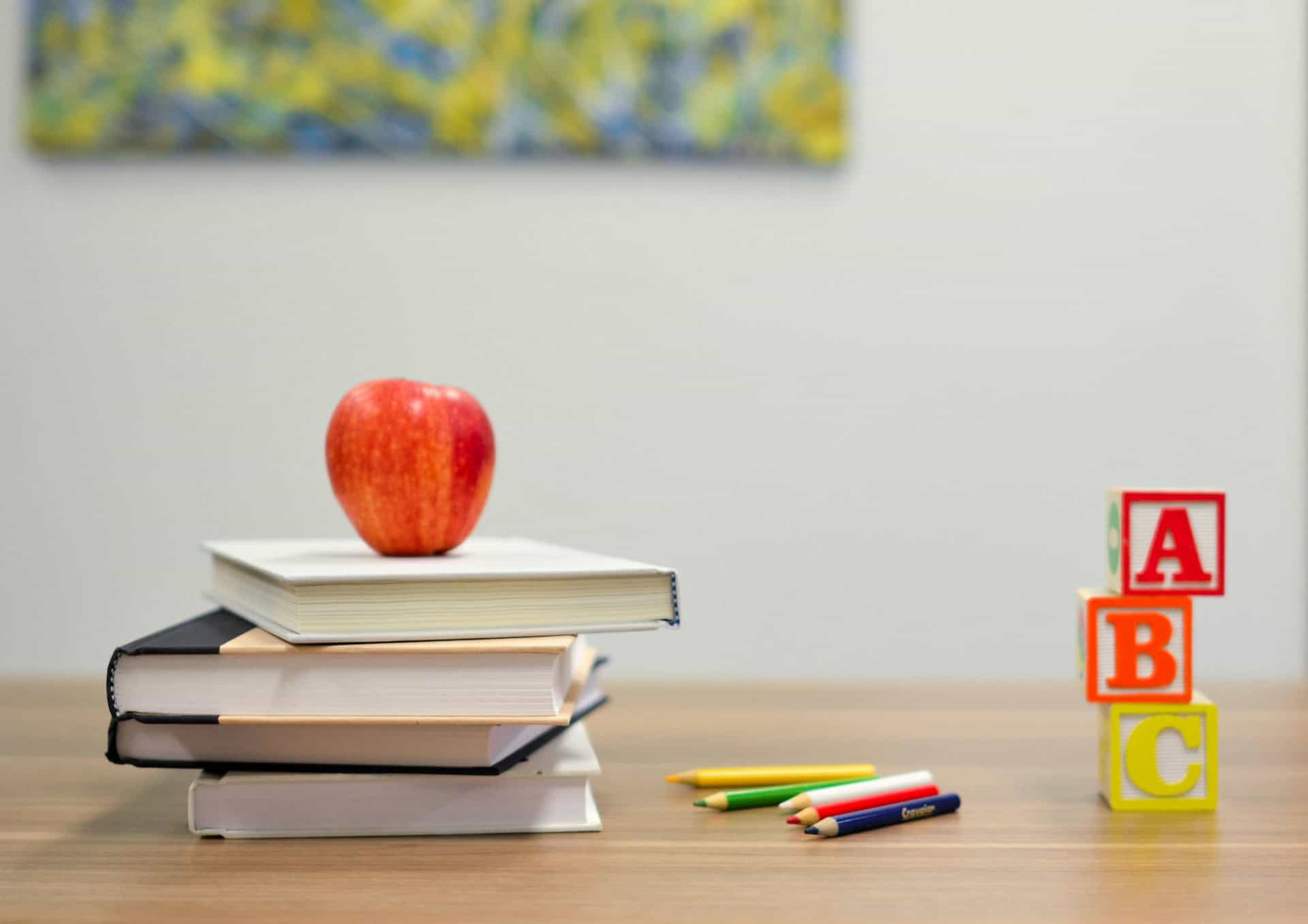 Books and apple and ABC blocks on a school desk