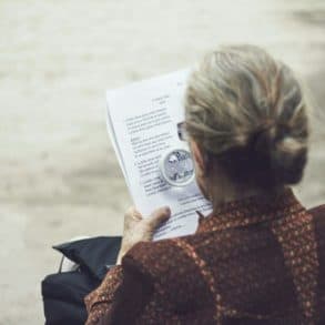 Older woman reading a French poetry book using a magnifying glass