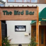 Front view of the The Bird Bar signage nestled in between signage for neighbouring properties