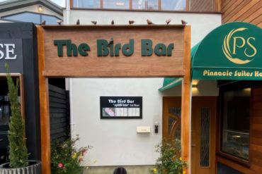 Front view of the The Bird Bar signage nestled in between signage for neighbouring properties