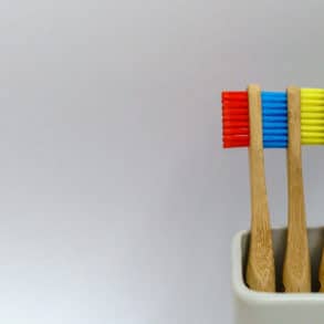 Toothbrushes in pot against plain background