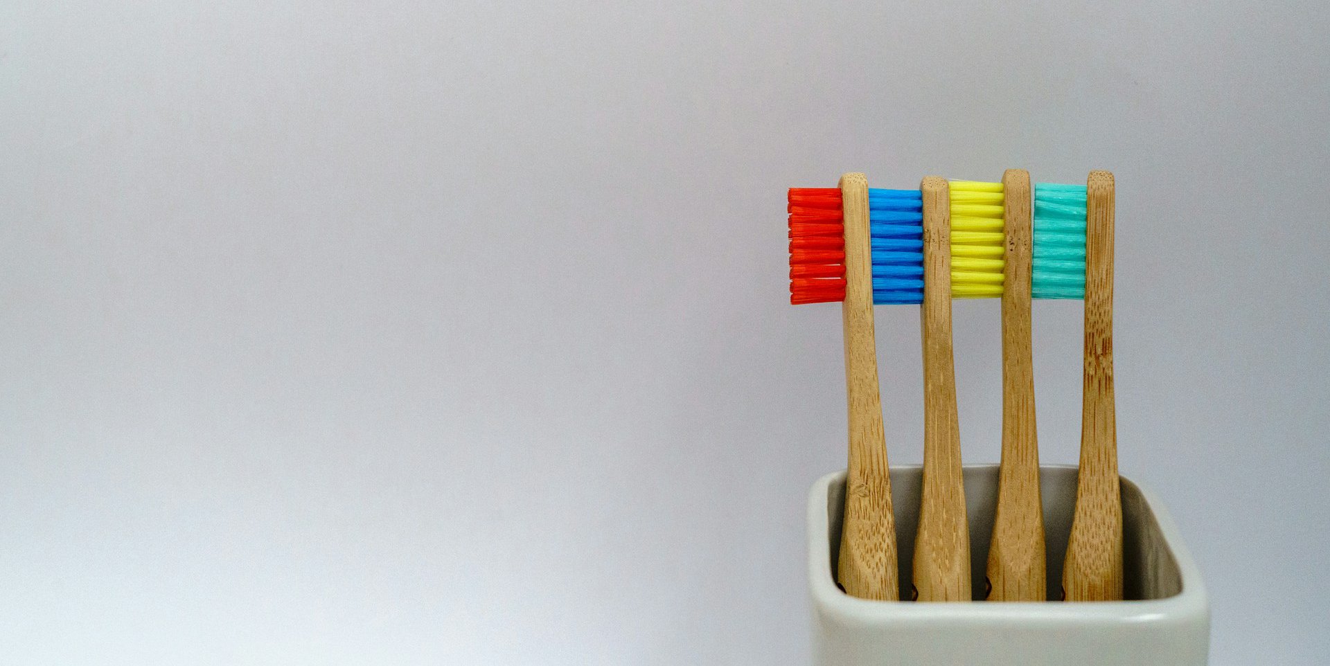 Toothbrushes in pot against plain background