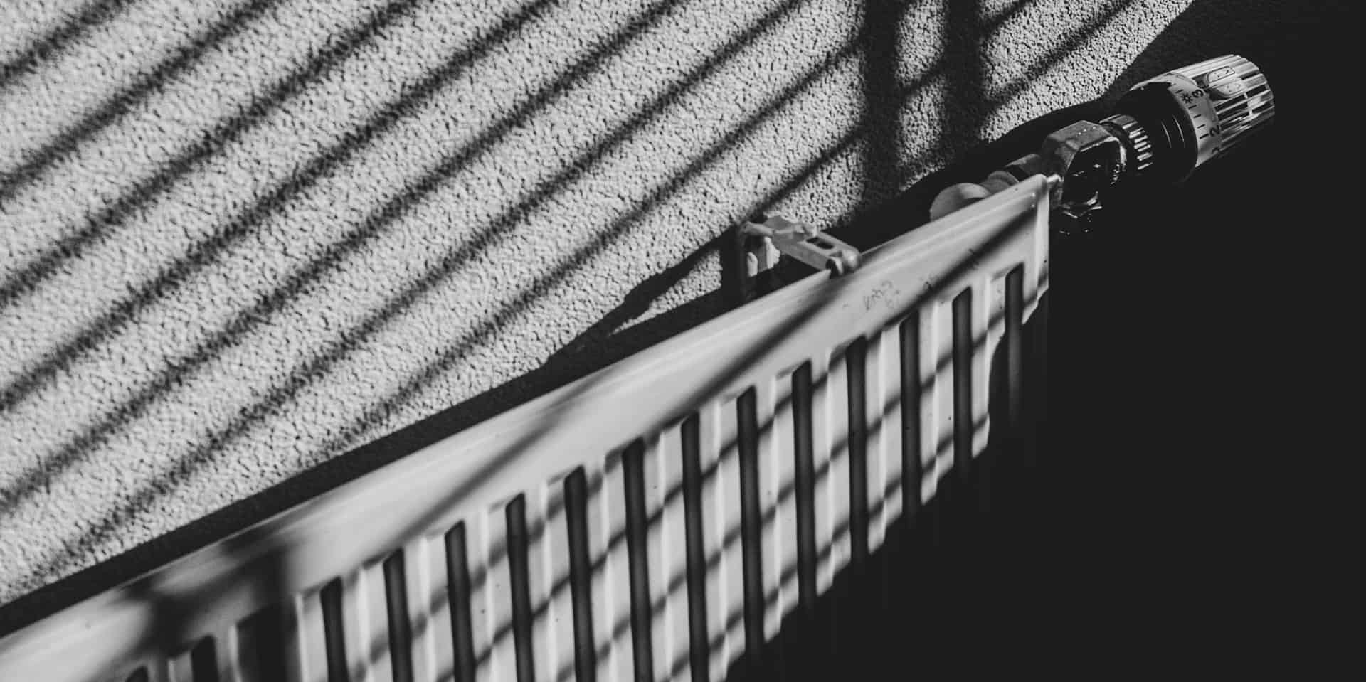 black and white image of a radiator with shadow of venetian blinds