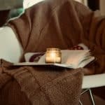 blanket draped over a chair with a book and lit candle on the chair