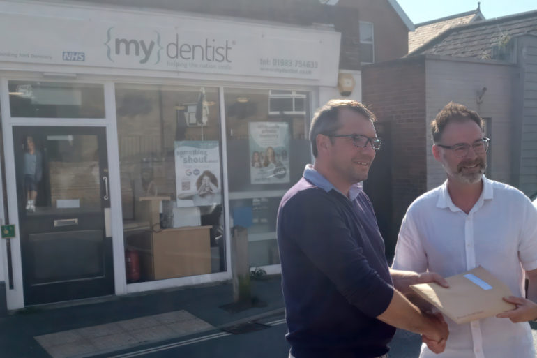 ieuan jehu handing over petition to richard quigley MP outside mydentist Freshwater