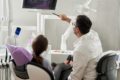 person in dentist chair with dentist looking at xrays