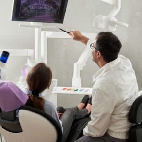 person in dentist chair with dentist looking at xrays