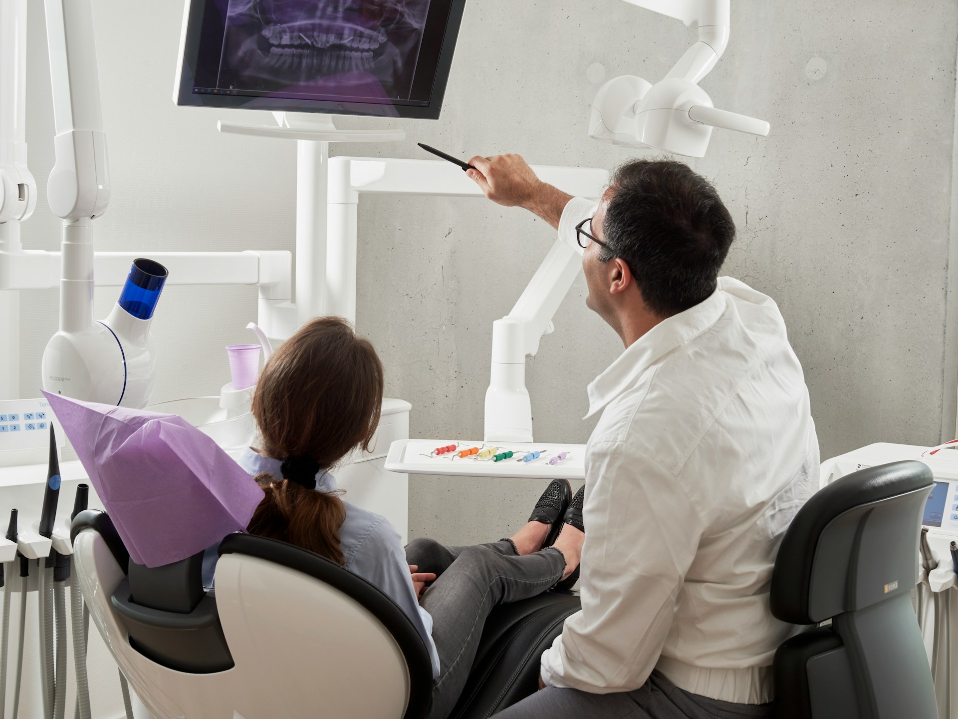 person in dentist chair with dentist looking at xrays