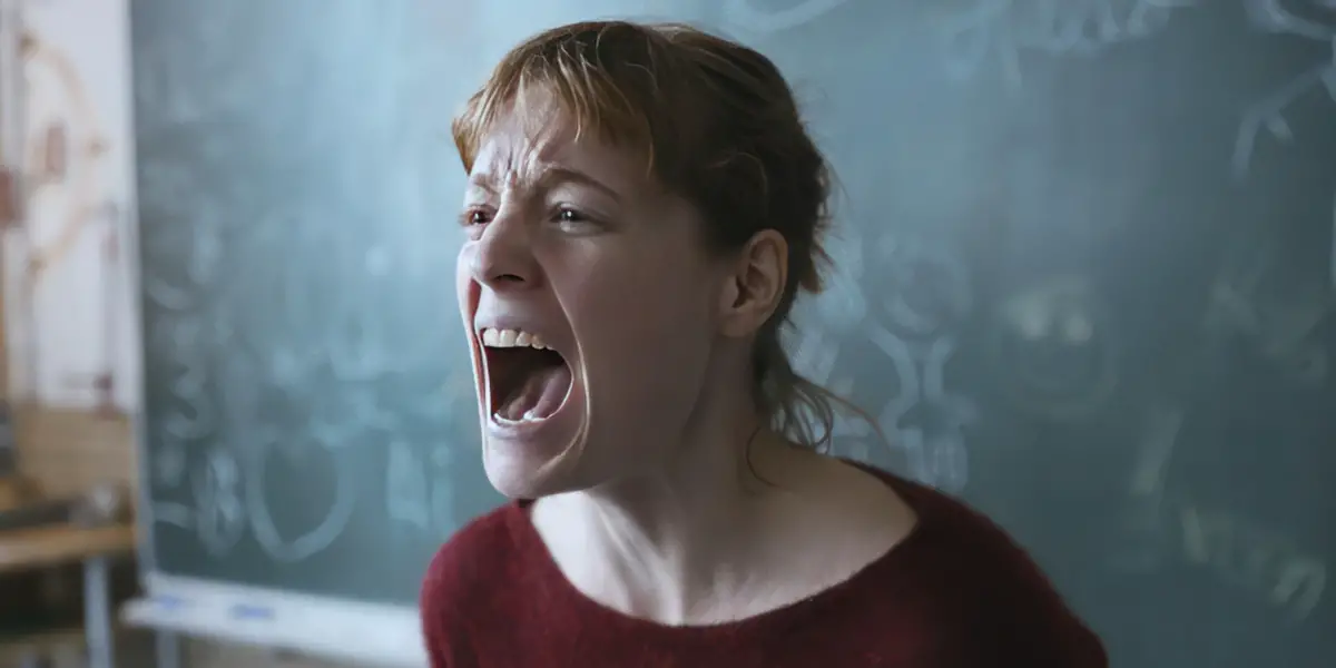 scene from The Teachers' Lounge showing a teacher standing by the blackboard screaming