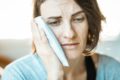 woman with toothache holding a cold compress to her cheek