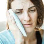 woman with toothache holding a cold compress to her cheek