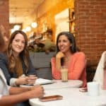 women of different ages sat talking at a table