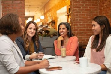 women of different ages sat talking at a table