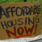 Cardboard plaque with 'affordable housing now' written on it