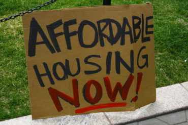 Cardboard plaque with 'affordable housing now' written on it