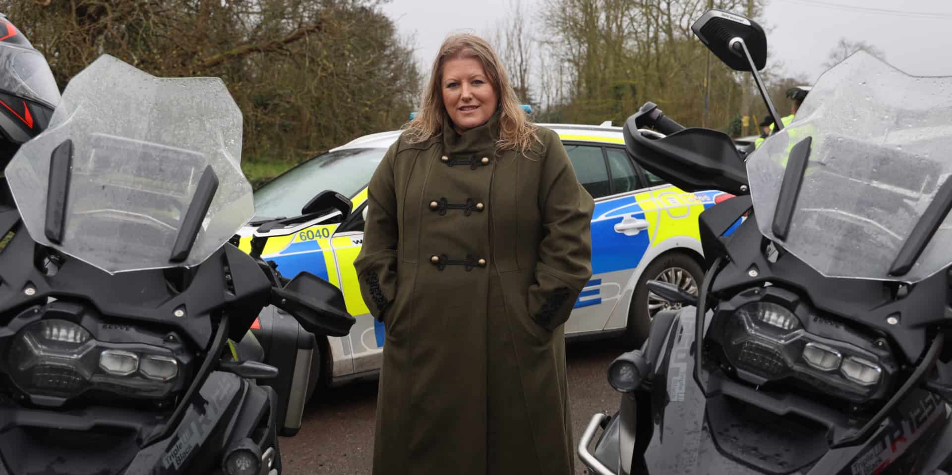 Donna Jones by police motorbikes and patrol car