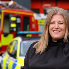 Donna Jones standing in front of a police car and fire engine