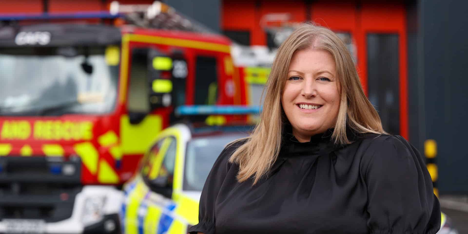 Donna Jones standing in front of a police car and fire engine