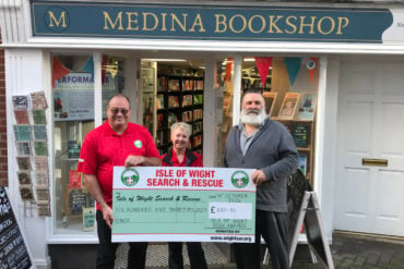 Dean Terrett, Paul Armfield and Jennifer Johnston standing outside the bookshop with a giant cheque