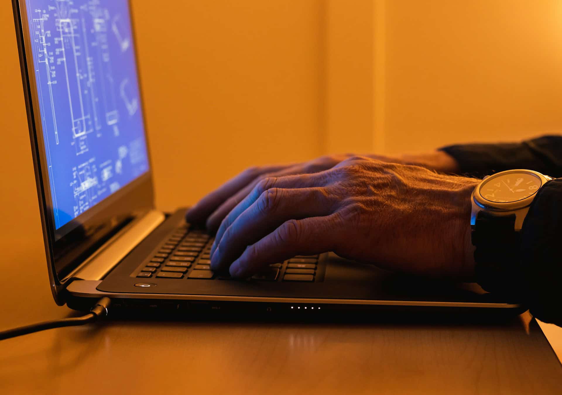 Man on laptop looking at blueprints