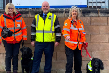 WightSAR Trainee Search Dog handler Catherine Fitton with Ginny, Wightlink Island Port Operations Manager Martin Gulliver and Trainee Search Dog handler Jasmine Light with Malli