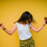 Teenage Girl dancing against a yellow background