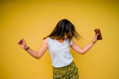 Teenage Girl dancing against a yellow background