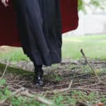 ground shot of woman in boots and long cape walking through grounds of appuldurcombe