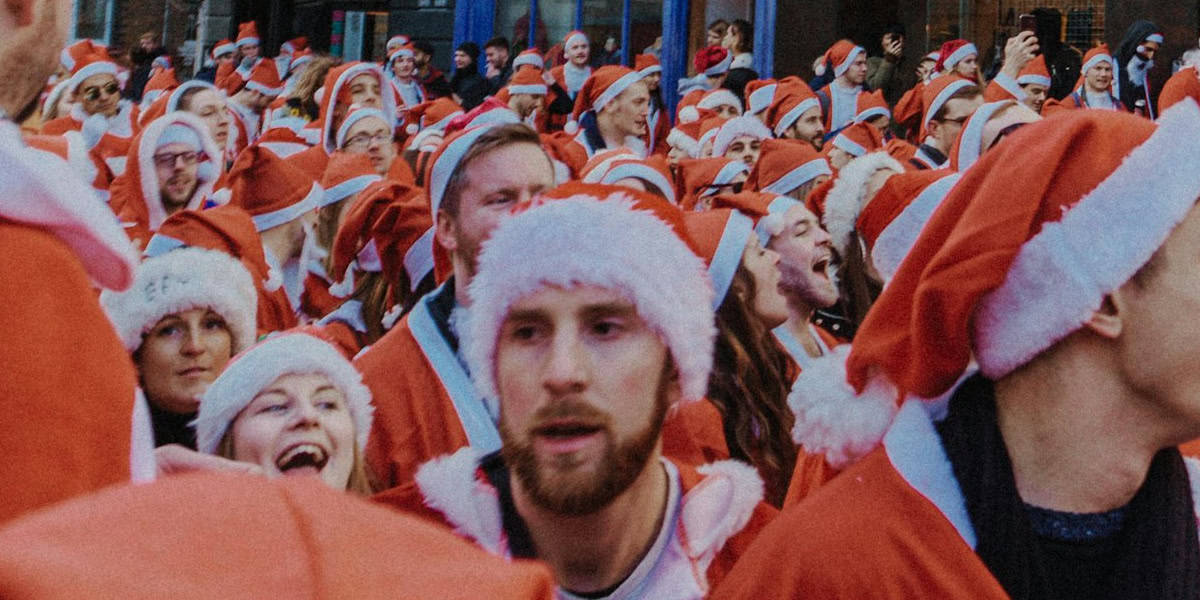 Lots of people dressed up in santa outfits taking part in a charity run