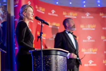 Fran Collins speaking at the podium during the awards ceremony