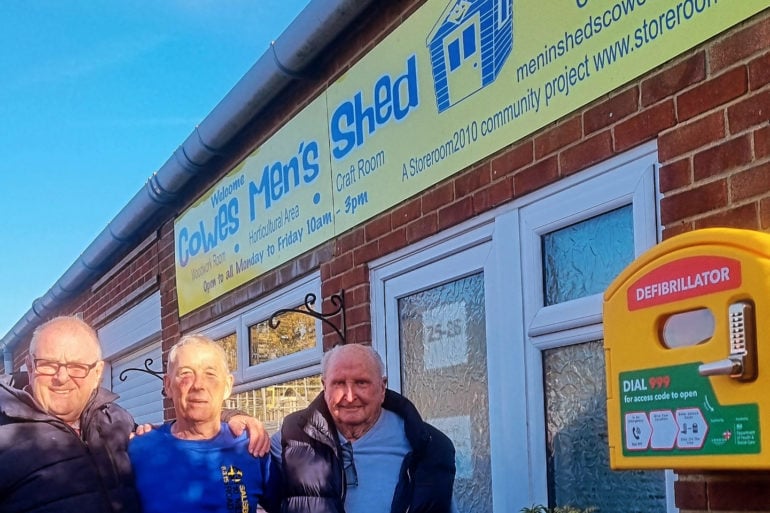 Members of Cowes Men's Shed outside with the newly installed defibrilator