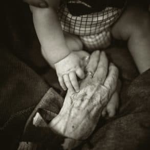 Baby touching hands with elderly relative