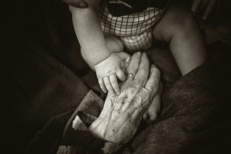 Baby touching hands with elderly relative