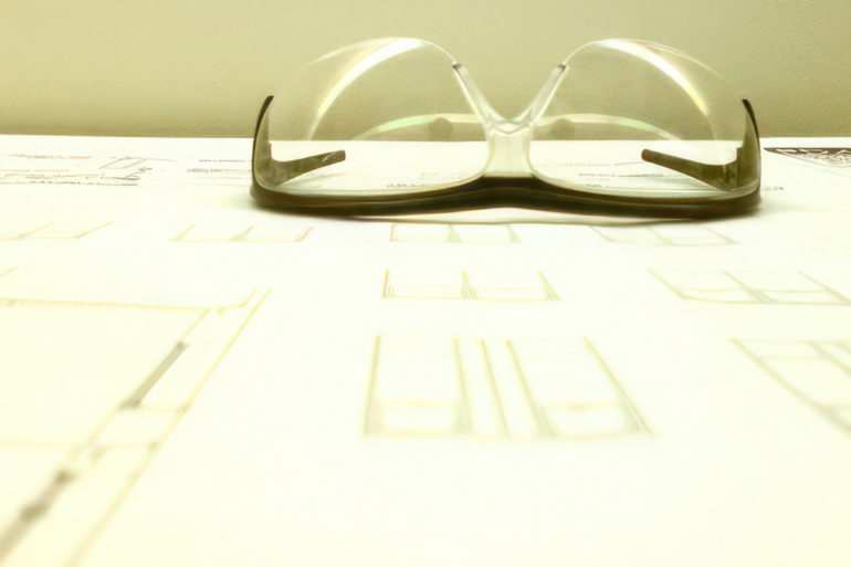 Pair of safety glasses sitting on blueprints for building