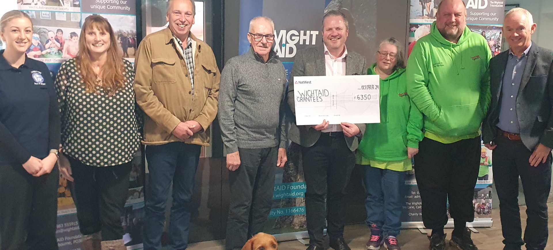 Representative of IW Pony Club, Cat, a nursery nurse from the neonatal unit, Graeme Burnett from Ventnor Cricket Club, representative of Ventnor Youth FC, Jon Carter, WightAID donor from Betapak, reps from Ventnor Carnival Association, and WightAID founder Geoff Underwood. Front is Mavis, the WightAID dog.