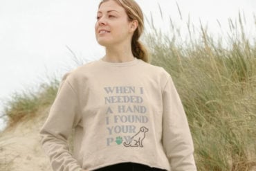 Woman on the beach wearing an ability dogs jumper